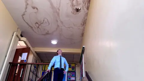 Holy Family School Principal John McCormack examining a leak in the school roof