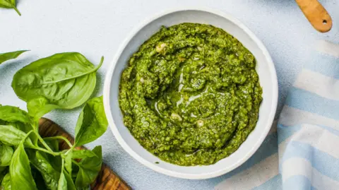 Getty Images A bowl of fresh pesto, containing pine nuts, basil, garlic, oil and parmesan