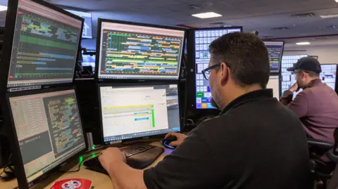 American Airlines A worker at Dallas Fort Worth International Airport watches multiple screens used to direct operations.