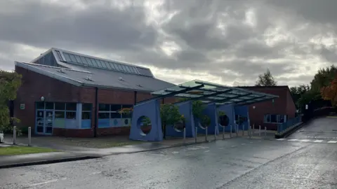 A red brick school building with a grey roof