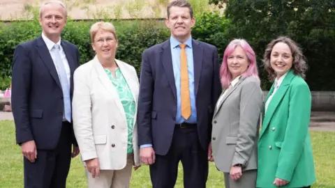 PA Media This image shows Rhun ap Iorwerth standing with his party's four newly-elected MPs in Westminster.  They are all smiling and looking at the camera.