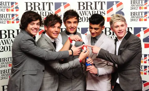 PA Media Five young men pose with an award on a red carpet 