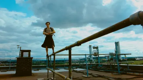 Mubi Film still from Bird showing Franz Rogowski standing on a metal fence