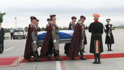 BBC Alex Salmond coffin draped in Saltire surrounded by members of the North Macedonian military