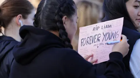 PA Media A fan in Liverpool writing a message for Liam Payne, which reads "RIP Liam: Forever Young"