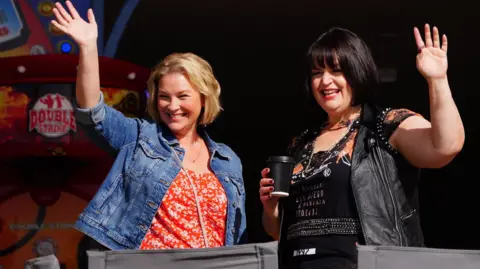 PA Media Joanna Page and Ruth Jones smile and wave to crowds of fans whilst filming in Barry Island