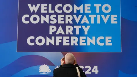 Getty Images A delegate takes a photo of the welcome sign at the second day of the Conservative Party Conference at Birmingham ICC Arena